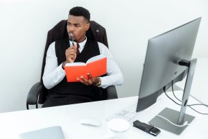 man in black suit holding a notebook and pen