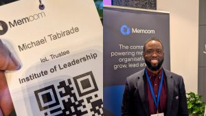 Michael Tabirade smiling at the Memcom conference in London, shown alongside a close-up of his Institute of Leadership Trustee event badge.